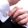 Concrete Cufflink blue-white being adjusted by a suited man