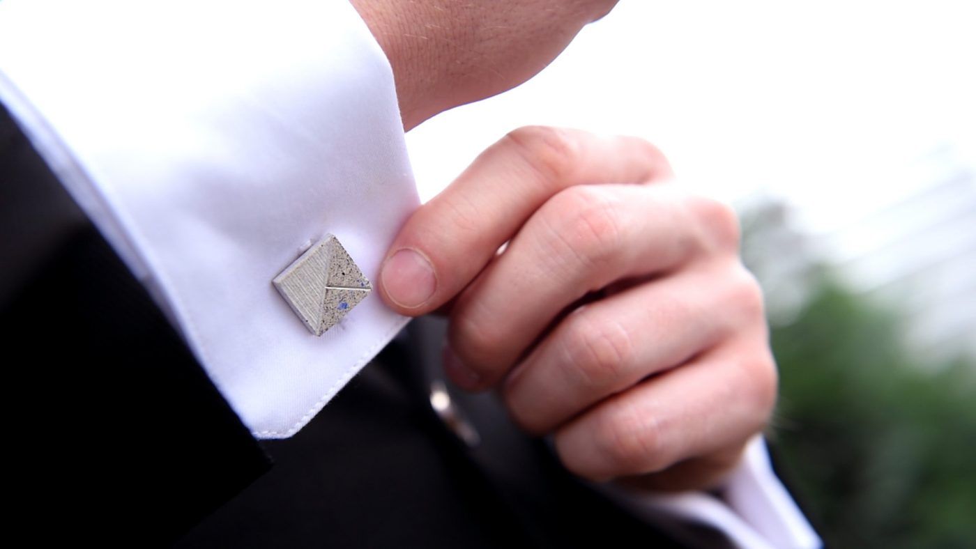 Concrete Cufflink blue-white being adjusted by a suited man