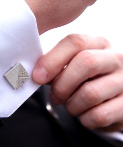 Concrete Cufflink blue-white being adjusted by a suited man